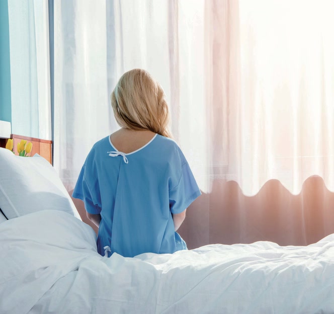 Patiente portant un vêtement médical dans une chambre de soins.