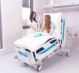 Patiente dans un lit hospitalier avec une soignante à ses côtés